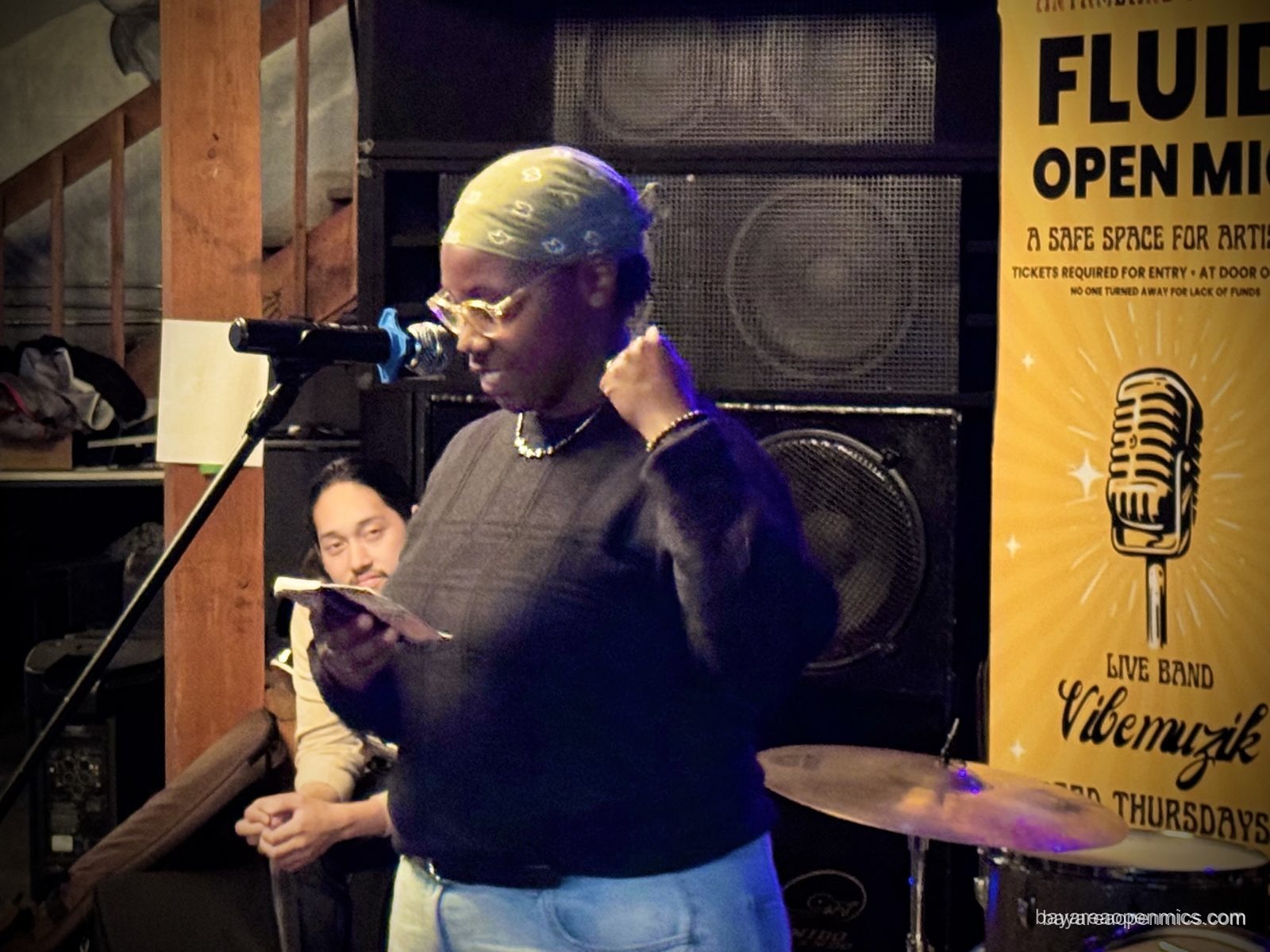 A performer takes the stage late in the evening at the Fluid open mic