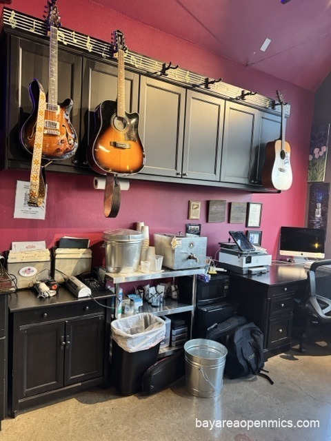 Guitar hangers mounted over wooden cabinets near the entrance of Pinot's Palette