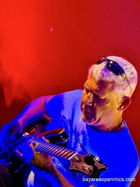 A dramatically colored photo of a white-haired man with sunglasses perched atop his head scowls in concentration while jamming at Pinot's Palette open mic in Livermore