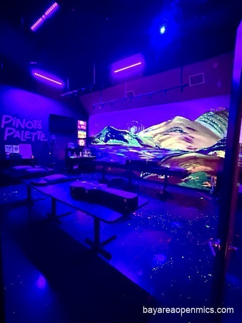 A blacklit storage room at Pinot's Palette casting everything in electric purple and blue