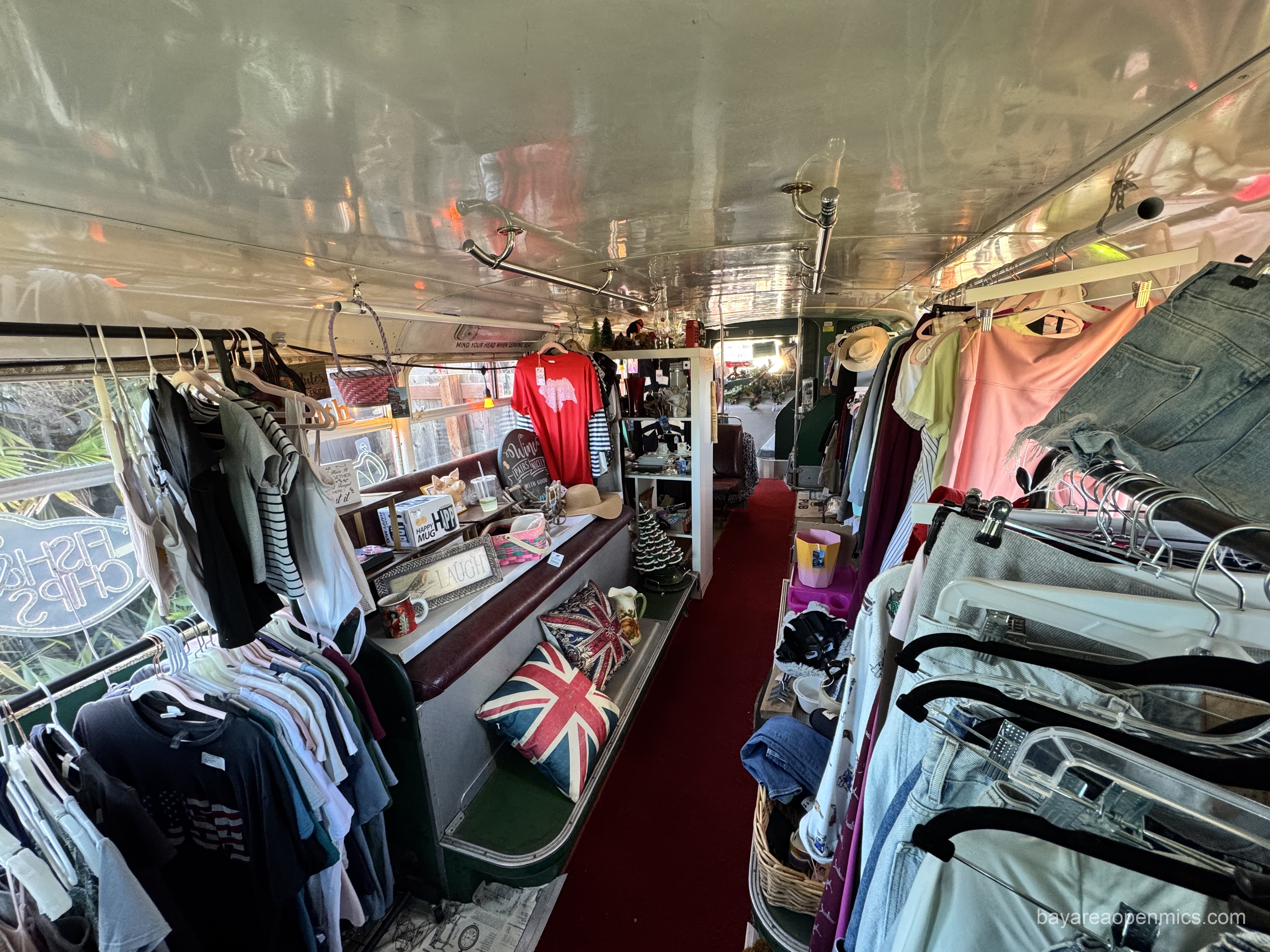 Union Jack pillows, hanging clothing, and knick-knacks clutter the downstairs of the bus