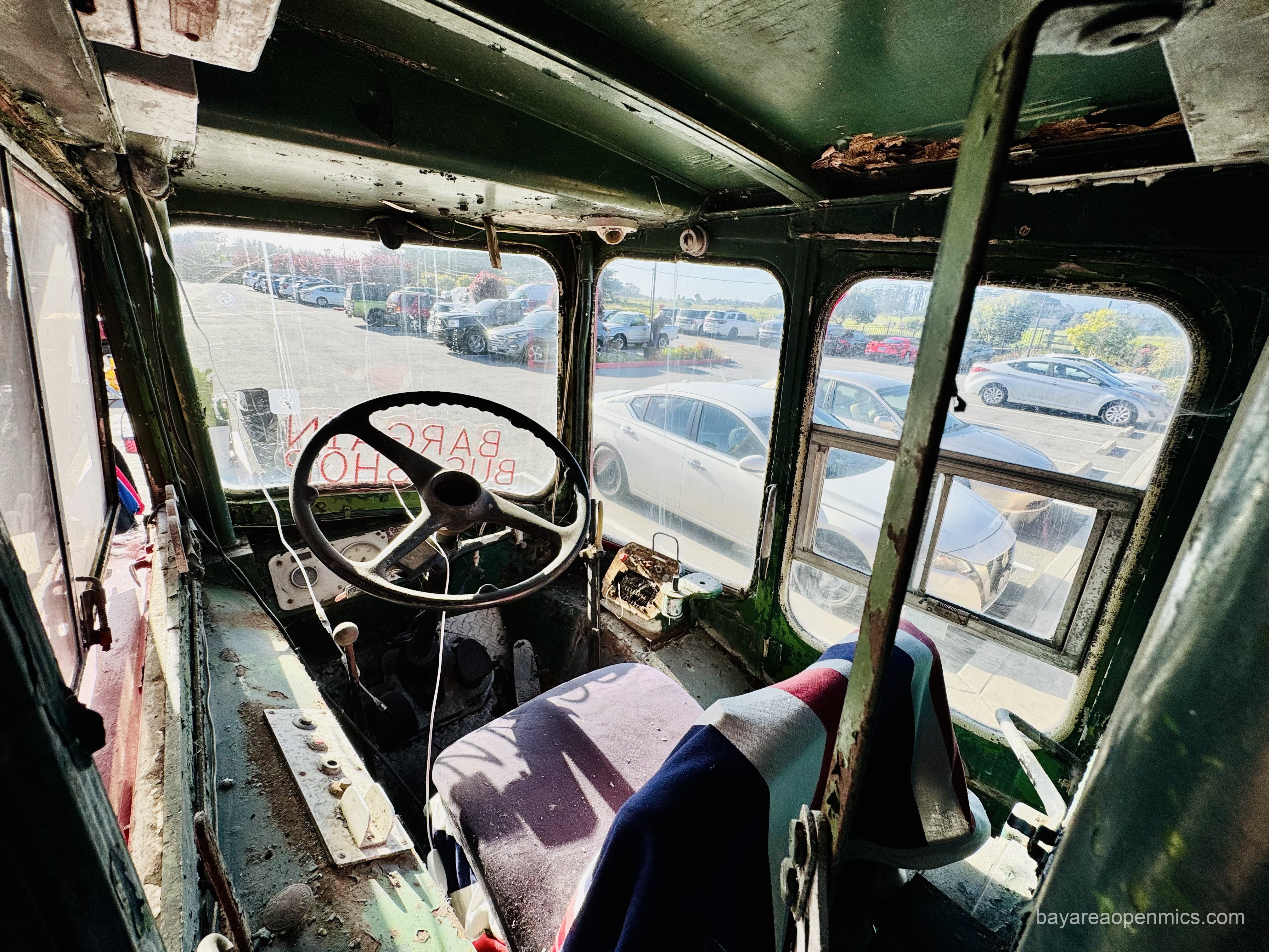 a cobwebbed steering wheel and discorporating seat of an old bus cockpit